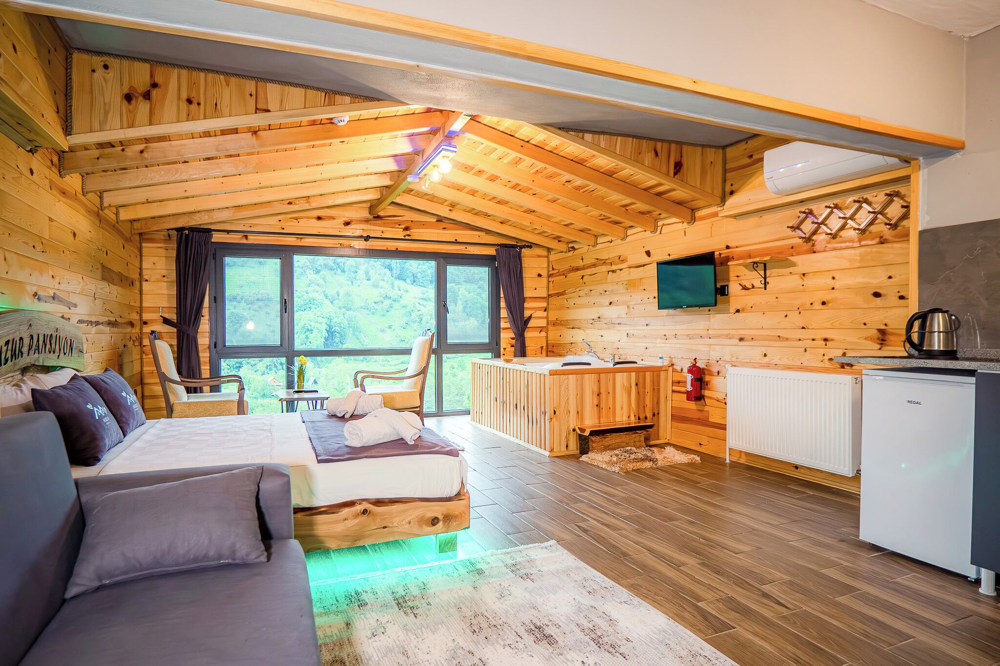 A wooden cabin with a bed, sofa, and kitchenette.