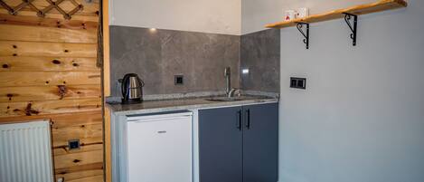 Una cocina funcional con refrigerador, lavamanos y cafetera.