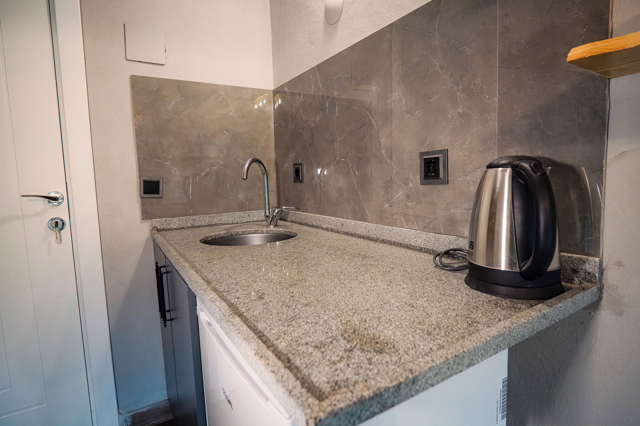 Eine Küche mit Granit-Arbeitsplatte, Spüle aus Edelstahl und einem Wasserkocher.