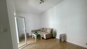A minimalist living room with a sofa, a small table, a radiator, and a ceiling fan. - El Patio de Tarifa II (tarifa)