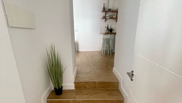 A staircase leading to a kitchen area with white walls and a potted plant. - El Patio de Tarifa II (tarifa)