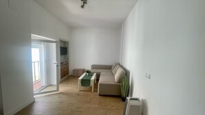 A living room with a sofa, a coffee table, a TV, and a ceiling fan. - El Patio de Tarifa II (tarifa)