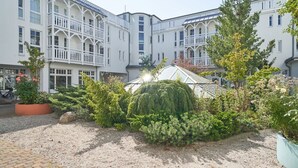 A courtyard with a greenhouse, surrounded by multi-story buildings with balconies. - Ferienwohnung in Sellin mit Balkon (Sellin)