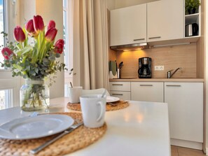 A modern kitchen with white cabinets, a coffee maker, and a vase of red tulips on the counter. - Ferienwohnung in Sellin mit Balkon (Sellin)