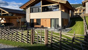 Ein modernes, zweistöckiges Gebäude mit Holzfassade, großen Fenstern und einem Steinsockel.