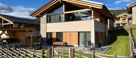 Un bâtiment moderne à deux étages, doté d’une façade en bois, de grandes fenêtres et d’un socle en pierre.