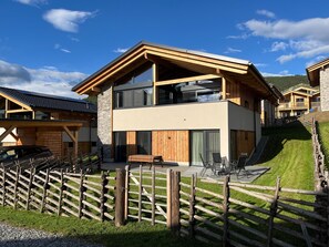 Ein modernes, zweistöckiges Gebäude mit Holzfassade, großen Fenstern und einem Steinsockel.
