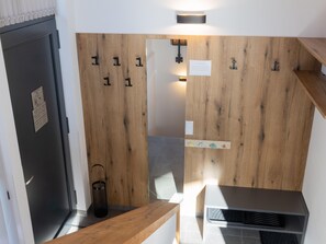 Ein modernes Badezimmer mit einer Holzvertäfelung, einer schwarzen Tür, einem Handtuchhalter, einem Spiegel und einer Duschkabine.