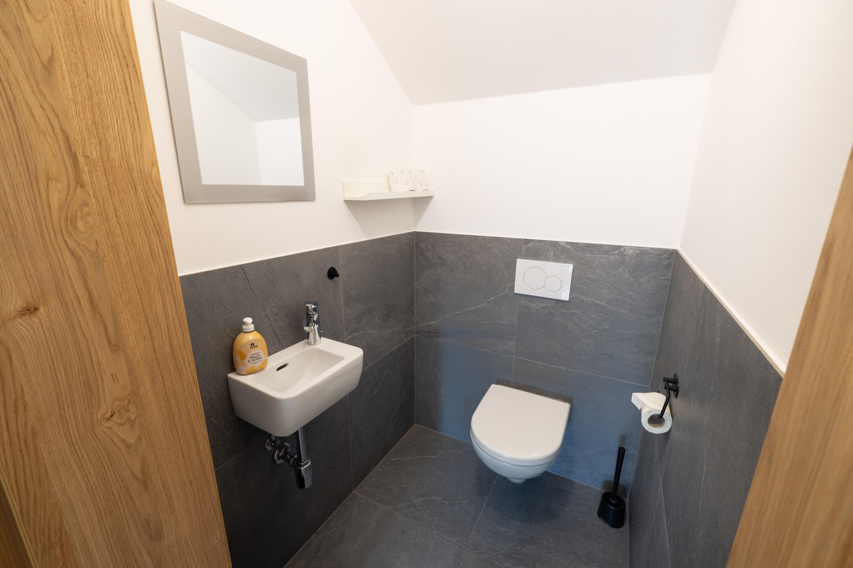 Een compacte badkamer met een wastafel, toilet en spiegel.