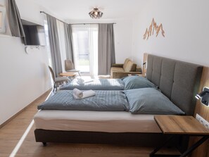 A hotel room with a bed, a desk, a chair, a TV, and a window with curtains. - Ski-in/ski-out Chalet With Beautiful View (Sankt Lambrecht)