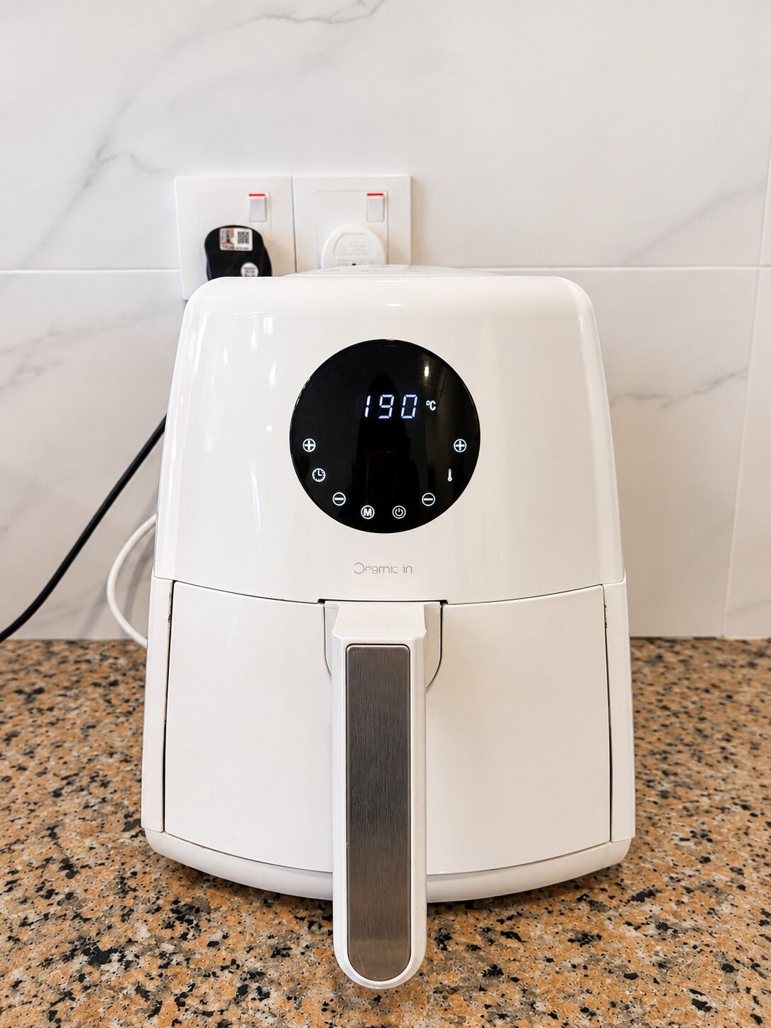 A white air fryer on a granite countertop with a digital display showing 190°C.