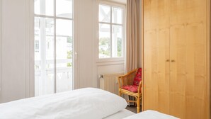A hotel room with a bed, a chair, a wardrobe, and large windows. - Ansprechende Ferienwohnung mit Balkon und Badewanne in Sellin (Sellin)