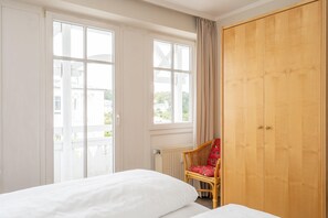 Ein Hotelzimmer mit einem Bett, einem Sessel, einem Kleiderschrank und großen Fenstern.