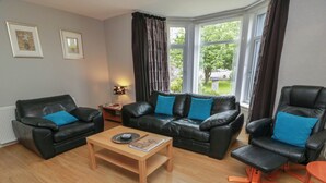 A living room with a sofa, armchairs, a coffee table, and a rug. - 1 St. Catherines Cottages (Perth)