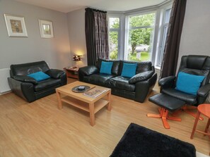 A living room with a sofa, armchairs, a coffee table, and a rug. - 1 St. Catherines Cottages (Perth)