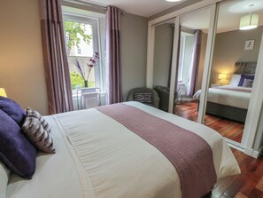 A hotel room with a bed, a chair, a desk, and a view of another room. - 1 St. Catherines Cottages (Perth)