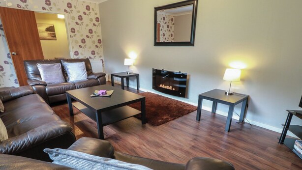 A living room with a sofa, coffee table, and TV stand. - Cliff View (Perth)