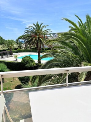 Piscina rodeada por palmeiras e um céu azul límpido.