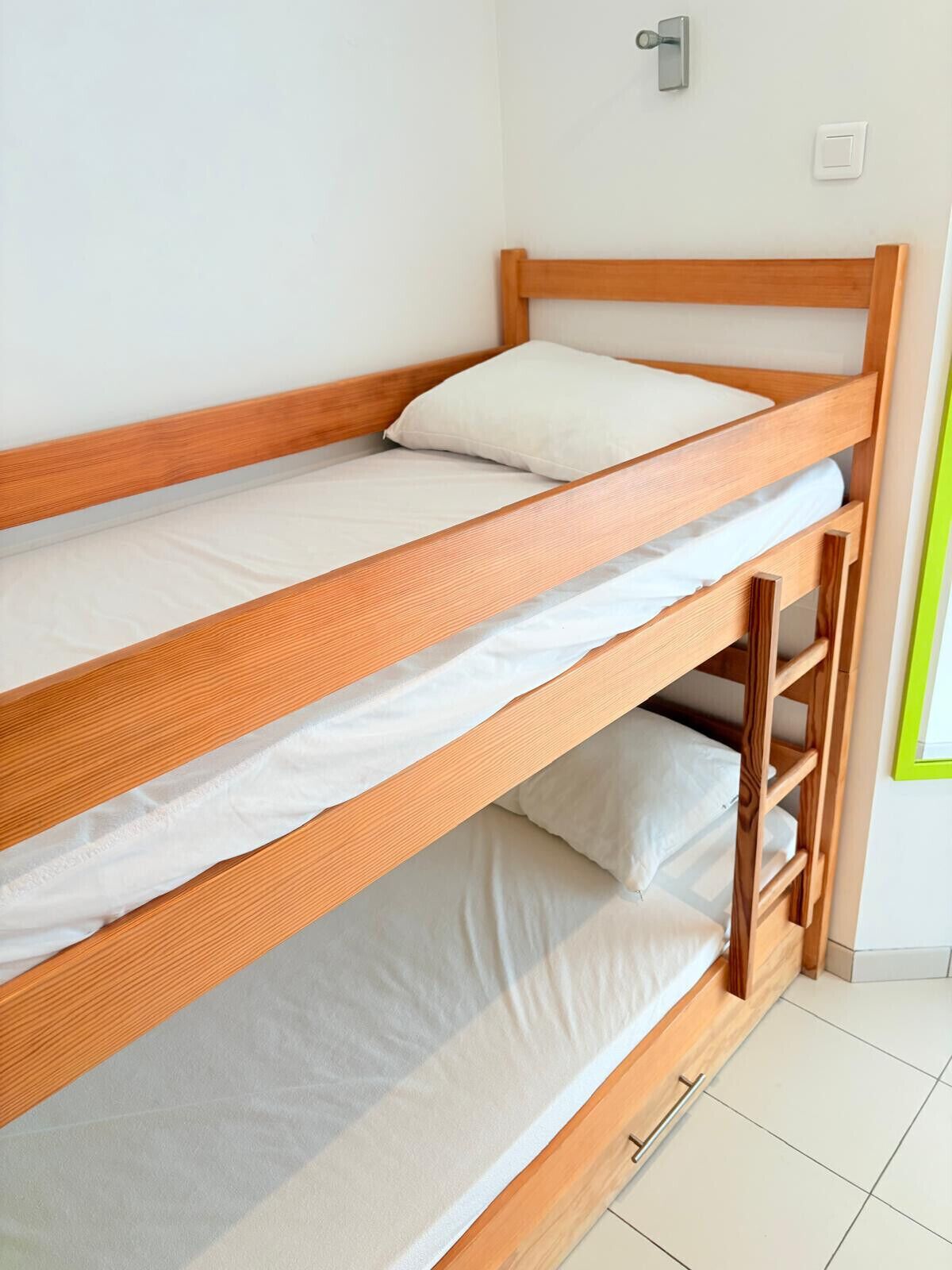 A bunk bed with two levels, a wooden frame, and white bedding.