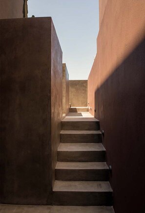 A narrow, concrete staircase leading up to a higher level, flanked by plain walls. - Serenity Villa, Anzo Villas (Thira - Santorini)