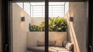 Ein modernes Interieur mit einer eingebauten Bank, einer Wandleuchte und einem großen Fenster mit Blick auf Grünflächen.