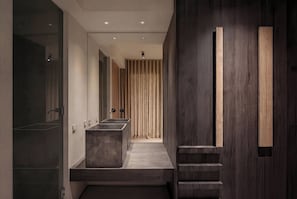 Ein modernes Badezimmer mit einem zentral platzierten Waschbecken, einem Spiegel und einer Holzpaneel-Verkleidung.