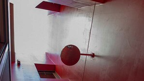 Ein rotes Interieur mit einem runden Objekt an der Wand und einem kleinen Tisch mit einer Flasche darauf.