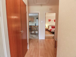 A hallway leading to a bedroom with a bed, a nightstand, and a lamp. There is a dining area with chairs and a table. - 2 St. Catherines Cottages (Perth)