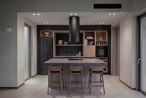 Eine moderne Küche mit Kochinsel, Barhocker, integrierten Geräten und einem eleganten Design.