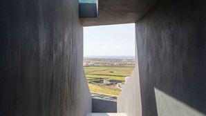 A corridor with a view of a landscape through a concrete structure. - Dreamscape Villa, Anzo Villas (Thira - Santorini)