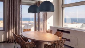 A modern dining area with a large table, wicker chairs, and pendant lights. - Dreamscape Villa, Anzo Villas (Thira - Santorini)