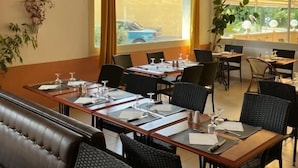 En restaurang med ett långt bord dukat för middag, en soffa och stolar.