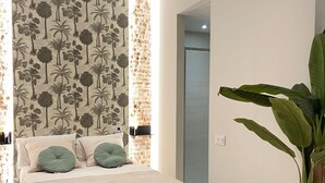 Ein Schlafzimmer mit einem Bett, einer großen Pflanze und einer Wand mit Palmenmuster.