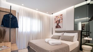 A modern bedroom with a large bed, a wooden wardrobe, a desk, and a mirror. - Premium Seaview Suite With Heated Pool and Private Parking (Rethymno)