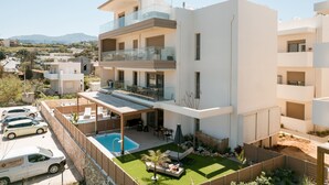 A modern multi-story residential building with a rooftop pool, outdoor seating, and a view of the surrounding landscape. - Premium Seaview Suite With Heated Pool and Private Parking (Rethymno)
