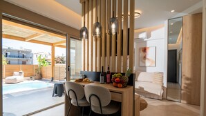 A modern kitchen with a wooden island, two chairs, a fruit bowl, and a dining table. - Premium Seaview Suite With Heated Pool and Private Parking (Rethymno)