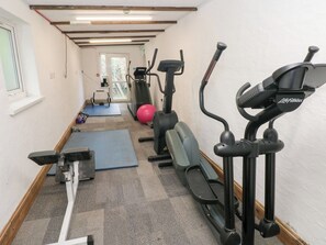 Un gimnasio con cintas de correr, elípticas y colchonetas de ejercicio.