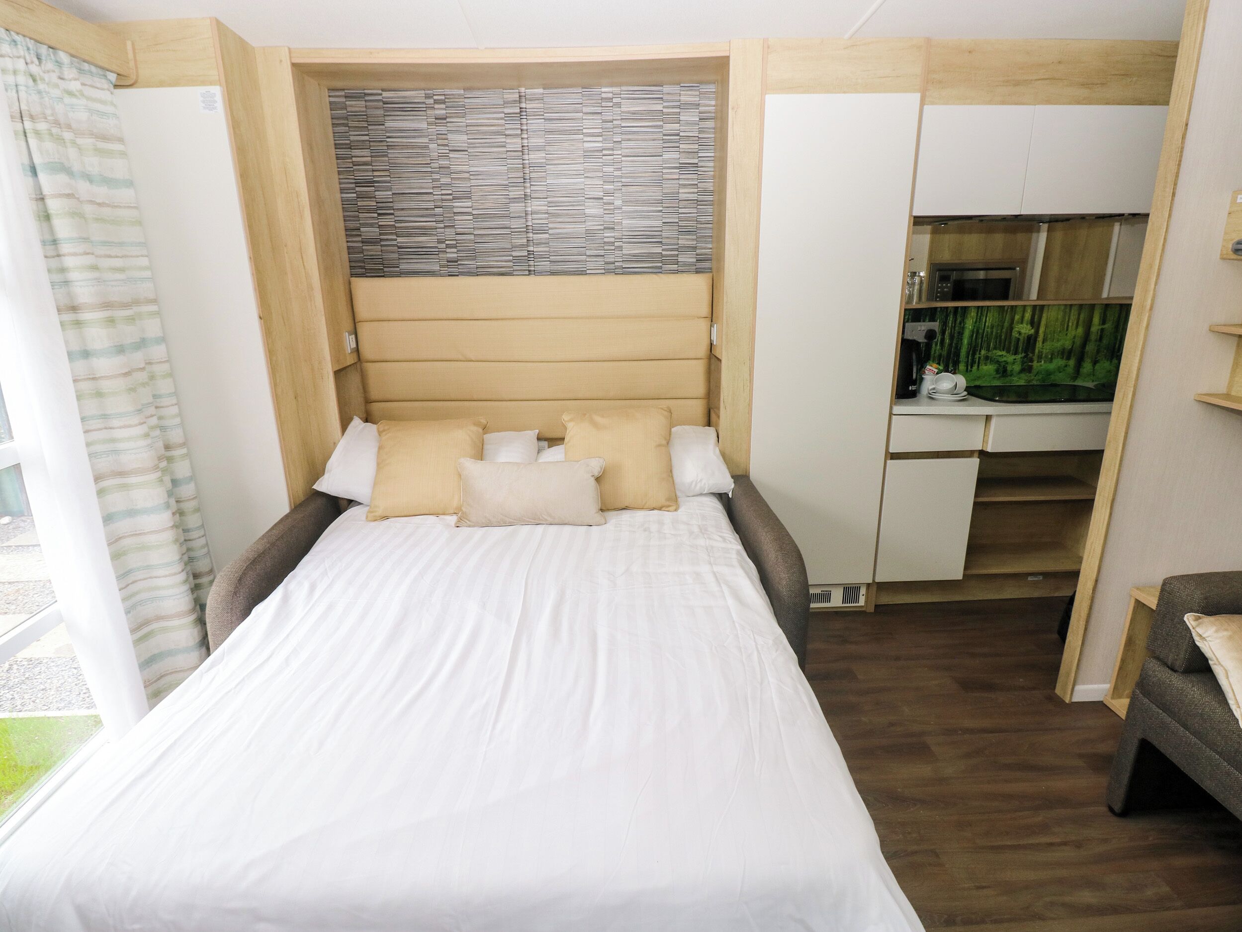 Ein Schlafzimmer mit Bett, Kissen, einem Kopfteil, einem Schreibtisch und einem Aquarium.