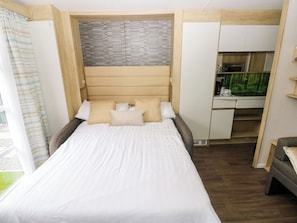 Un dormitorio con cama, almohadas, cabecera, escritorio y un acuario.