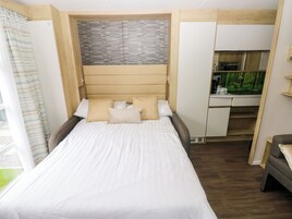 Un dormitorio con cama, almohadas, cabecera, escritorio y un acuario.