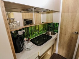 Una kitchenette compacta con microondas, pileta y un mueble pequeño.
