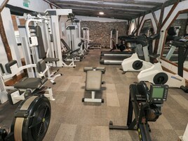 Un gimnasio con equipo de ejercicio variado, incluyendo cintas de correr, máquinas de pesas y una bicicleta estática.