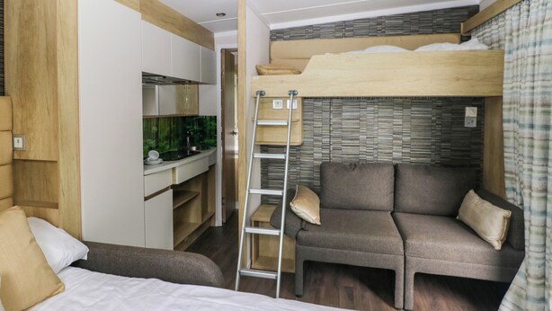 A bunk bed with a ladder, a sofa, and a small kitchenette. - Cwtch (Kidwelly)