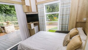 Un dormitorio con cama, televisión, escritorio y vistas al exterior.