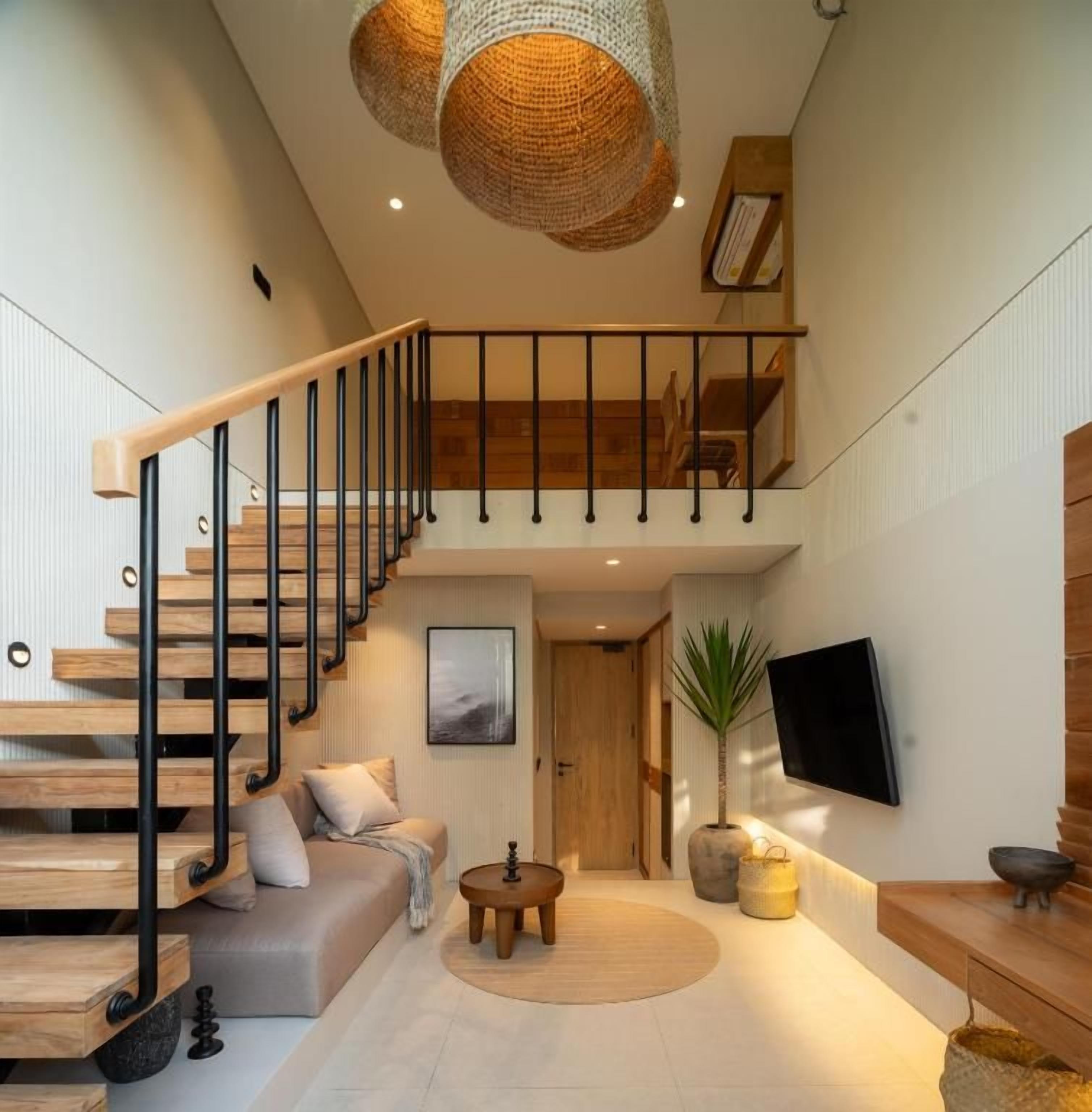 Un interior moderno con una escalera de madera, un televisor de pantalla plana y una zona de estar acogedora.