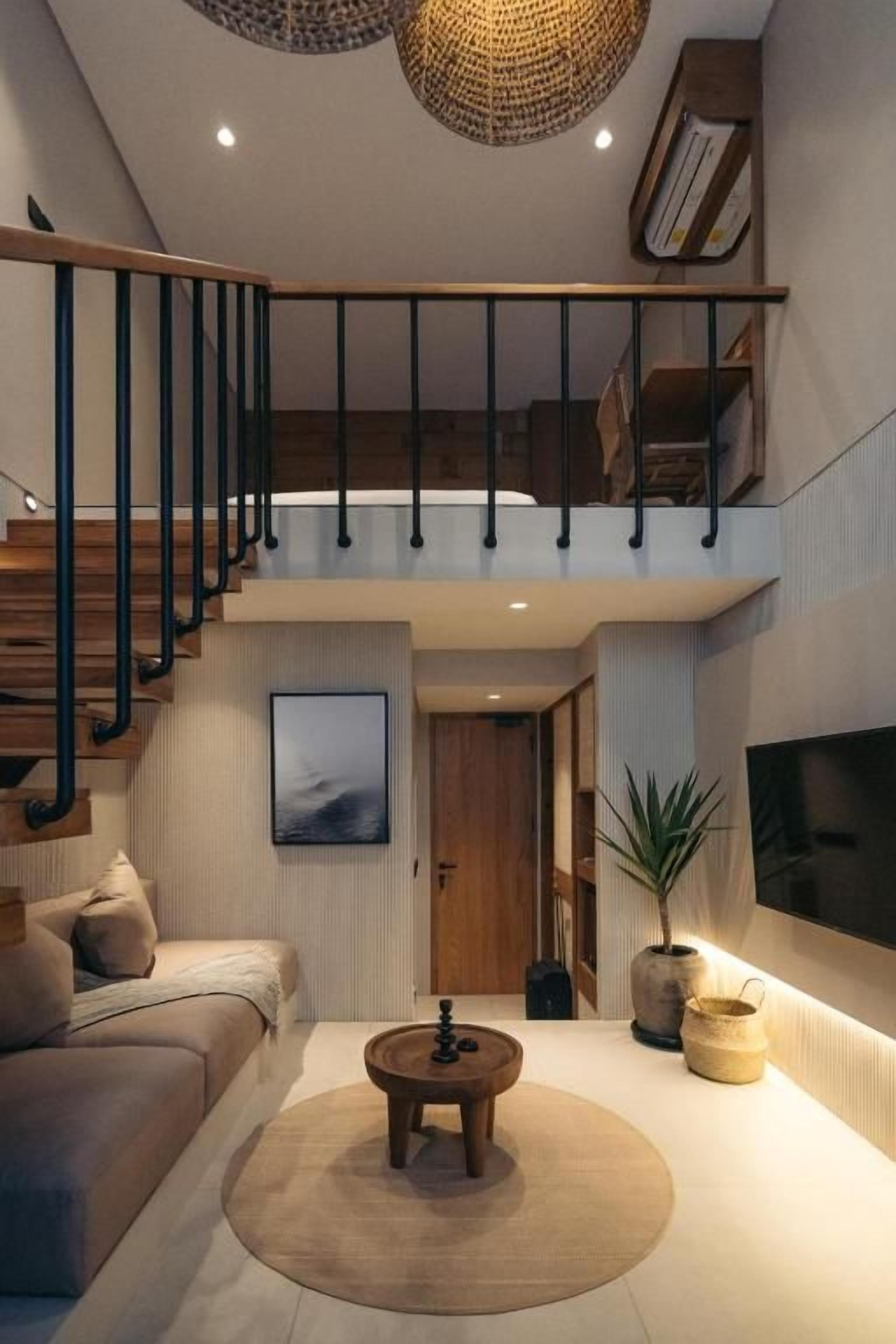 A modern living room with a staircase, a sofa, a coffee table, and a television.