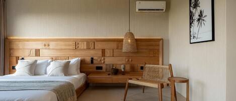 A hotel room with a large bed, a wooden headboard, a woven chair, and a framed picture on the wall.
