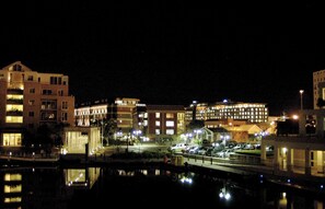 A nighttime view of a cityscape with buildings, a bridge, and a body of water reflecting lights. - Luxurious Secure 2 Bedroom V&A Waterfront Apt (Cape Town)