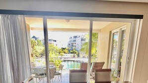 Ein Essbereich mit Tisch und Stühlen, große Fenster mit Vorhängen und Blick auf Gebäude und Grünflächen.
