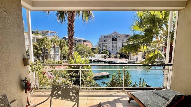 Ein Balkon mit Blick auf eine Marina, einem Esstisch und einer Couch.